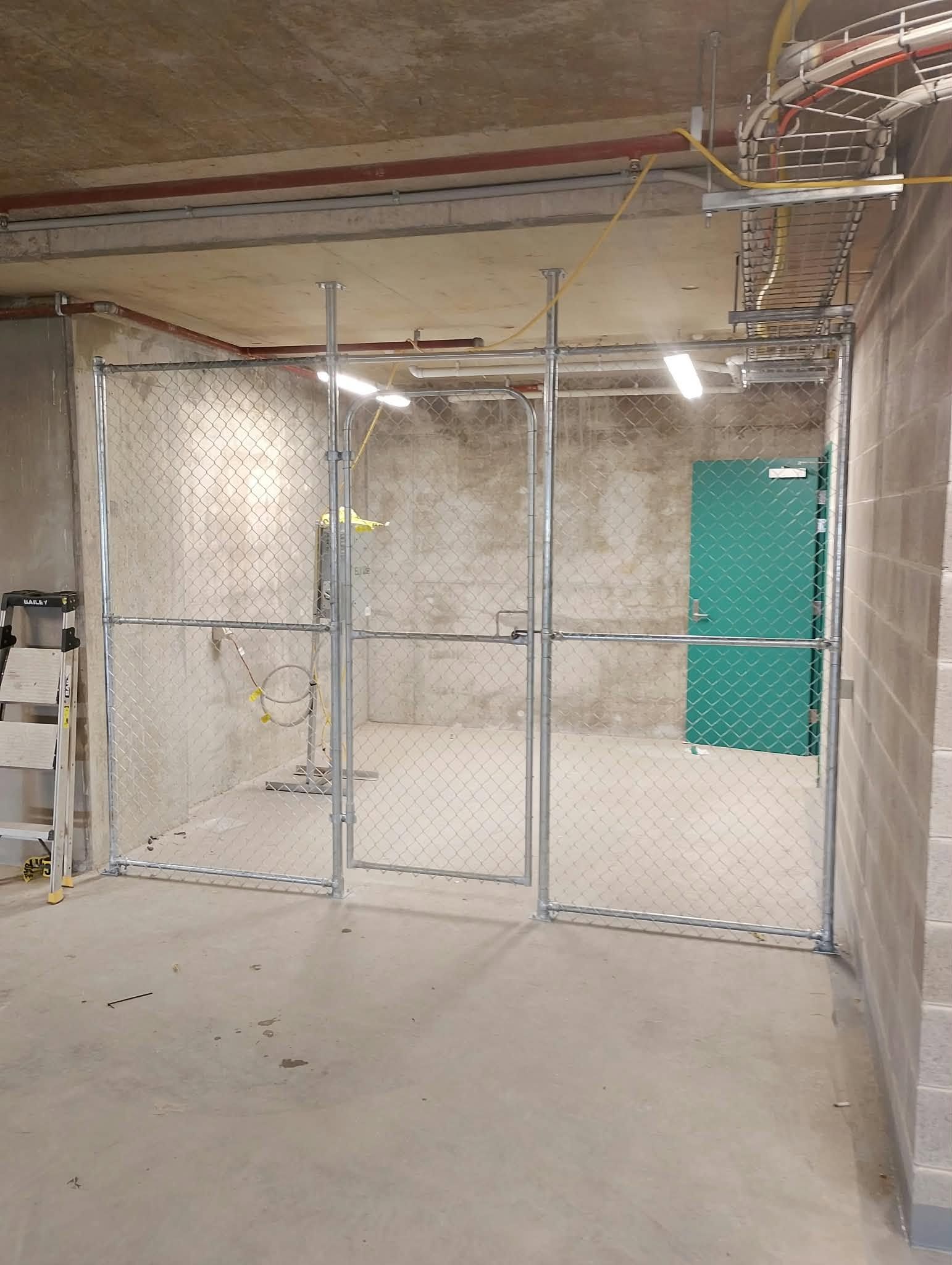 Mesh fence enclosure with matching mesh gate inside a concrete building